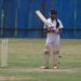 Female cricketer preparing to bat on a grass field (Pexels 13509971)