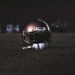 American football helmet on a darkened field at night, illustrating the Falcons vs Packers game at Lambeau