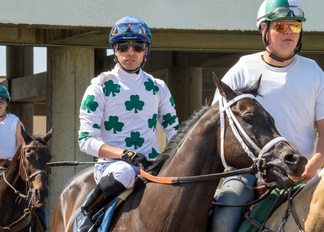 Jockey in green and white silks on a racehorse in the parade ring (Pexels 13154679)