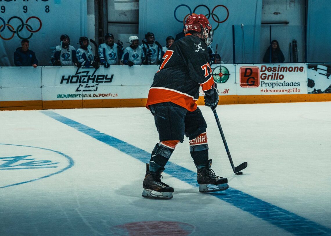 Ice hockey player skating with the puck in an indoor arena (Pexels 38555355)