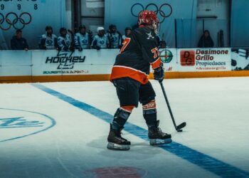 Ice hockey player skating with the puck in an indoor arena (Pexels 38555355)