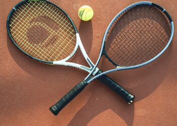 Two tennis rackets and a ball on a clay court (Pexels 27152933)